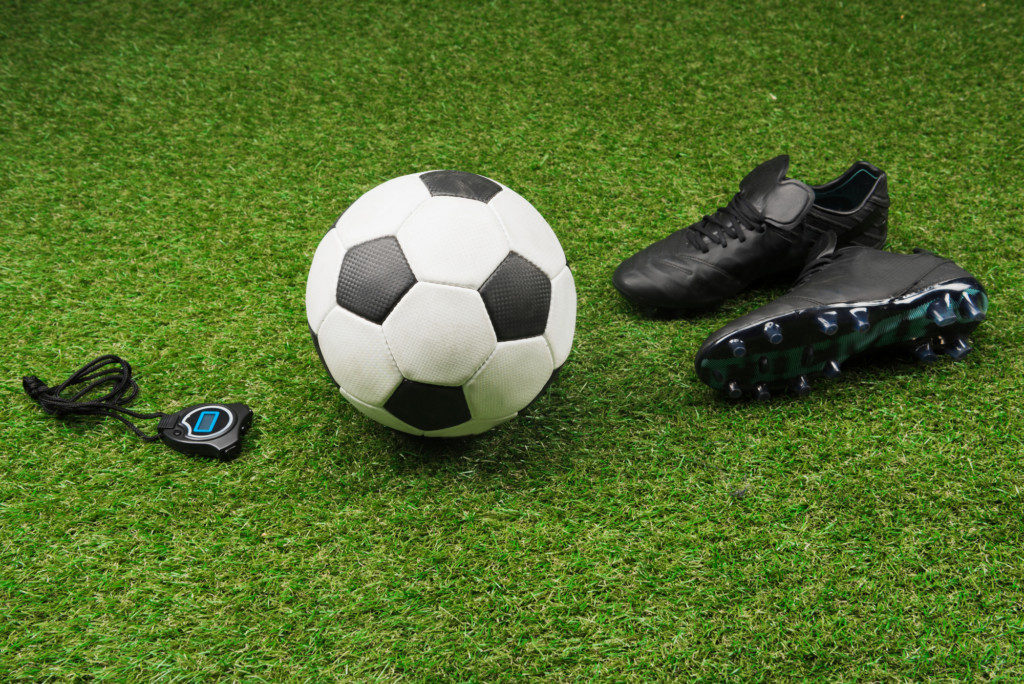 fodbold-og-fodboldstoevler-paa-groent-graes